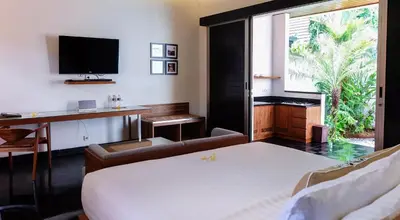 a bedroom with a bed and a desk and a television at Sun Island Boutique Villas & Spa Seminyak in Seminyak