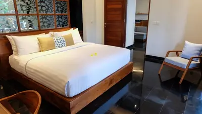 a bedroom with a bed and two chairs at Sun Island Boutique Villas & Spa Seminyak in Seminyak