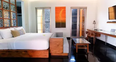 a bedroom with a bed and a table and a desk at Sun Island Boutique Villas & Spa Seminyak in Seminyak