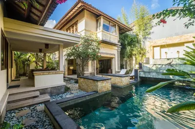 a house with a pond in front of a house at Villa Diana Bali in Legian
