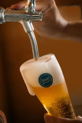 a beer is being poured into a glass at Four Points by Sheraton Bali, Seminyak in Seminyak