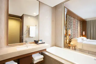 a bathroom with a sink and a mirror and a bed at Four Points by Sheraton Bali, Seminyak in Seminyak