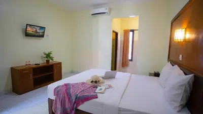 a bedroom with a bed with a laptop on it at Teges Inn Kuta in Kuta