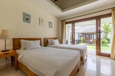 two beds in a room with a window at Villa Harmony Canggu in Canggu