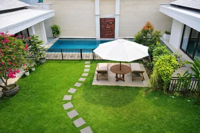 a patio with an umbrella and chairs and a pool at Villa Harmony Canggu in Canggu
