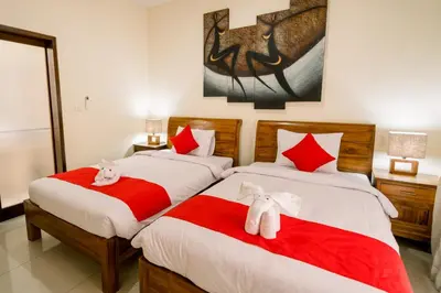 a bedroom with two beds with red and white sheets at Taman Bali Villas Dewi Sri in Legian