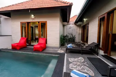 a house with a swimming pool and red pillows at Taman Bali Villas Dewi Sri in Legian