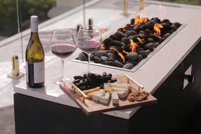 a table with two glasses of wine and a fire grill at The Jendela House in Canggu