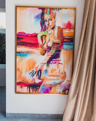 a painting hanging on a wall with a curtain at The Jendela House in Canggu