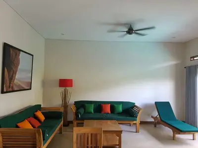 a living room with a green couch and a ceiling fan at Villa Rahayu in Seminyak