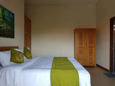 a bedroom with a white bed with green pillows at Villa Rahayu in Seminyak