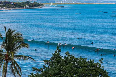 a group of people riding a wave in the ocean at The Kuta Beach Heritage Hotel - Managed by Accor in Kuta