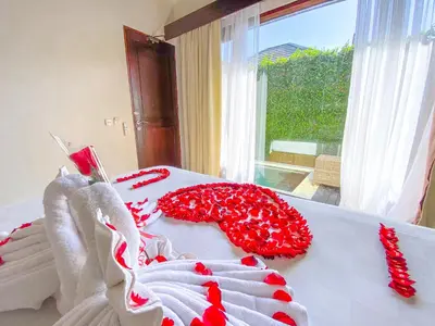 a white bed with red and white flowers on it at New Pondok Sara Villas in Seminyak