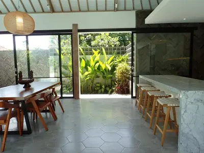 a dining room with a table and chairs and a counter at Villa Hujan in Seminyak