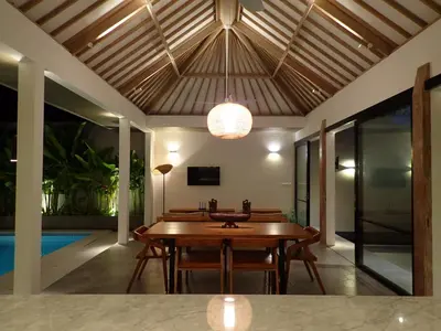 a dining room with a table and a chandelier at Villa Hujan in Seminyak