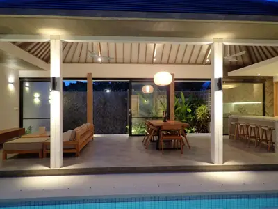 a patio with a table and chairs and a pool at Villa Hujan 2 in Seminyak