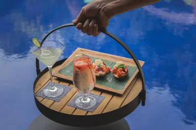 a person holding a tray with a drink and a plate of food at Villa Dewata One in Seminyak