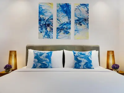 a bedroom with a bed with blue and white pillows at Avani Seminyak Bali Resort in Seminyak