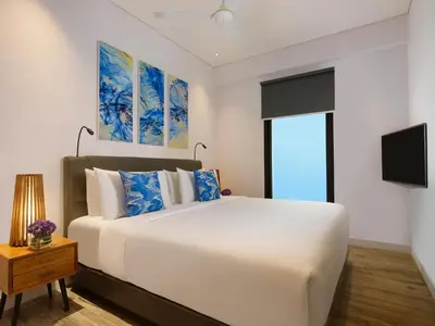 a bedroom with a large white bed and a tv at Avani Seminyak Bali Resort in Seminyak
