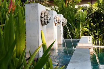a swimming pool with a fountain in a garden at Avani Seminyak Bali Resort in Seminyak