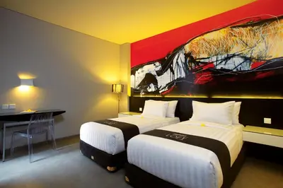 a hotel room with two beds and a painting on the wall at Loft Legian Hotel Bali in Legian