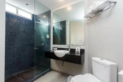 a bathroom with a sink and a shower and a toilet at Loft Legian Hotel Bali in Legian