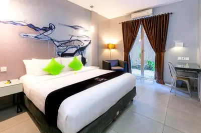 a bedroom with a large bed with green pillows at Loft Legian Hotel Bali in Legian