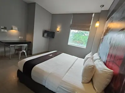 a hotel room with a bed and a desk at Loft Legian Hotel Bali in Legian