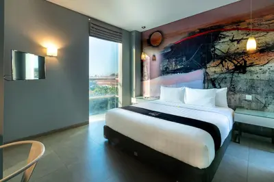 a bedroom with a large bed with a painting on the wall at Loft Legian Hotel Bali in Legian