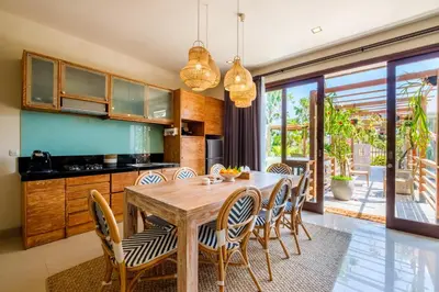 a kitchen and dining room with a wooden table and chairs at The Akasha Seminyak Bali Boutique Hotel in Seminyak
