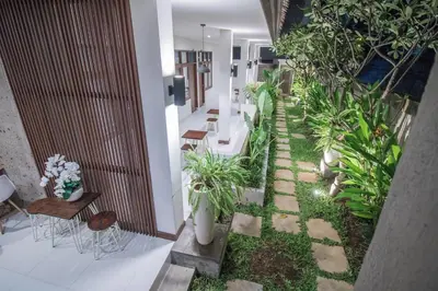 a courtyard with plants in a building at Kak Garden Inn in Kuta
