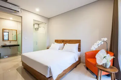a bedroom with a bed and an orange chair at Eclipse Kerobokan in Kerobokan