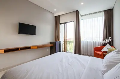 a bedroom with a bed and a tv and a chair at Eclipse Kerobokan in Kerobokan