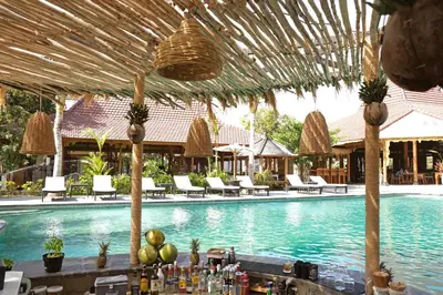 a resort pool with chairs and a bar with drinks at Kashantee Village in Seminyak