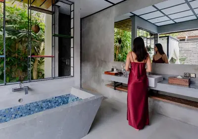a woman in a red dress standing in front of a bathroom at Vinna Villa Seminyak by The Wina Resorts in Kerobokan