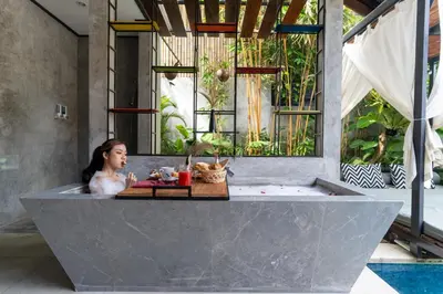 a woman sitting in a bath tub in a room at Vinna Villa Seminyak by The Wina Resorts in Kerobokan