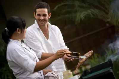 a man and a woman cooking food on a grill at The Kunja Villa-Hotel in Seminyak