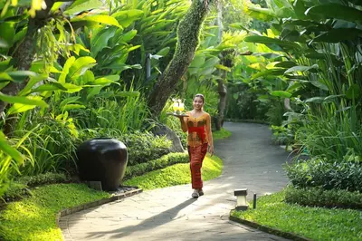 a woman walking down a path in a garden at Gending Kedis Luxury Villas & Spa Estate in Jimbaran