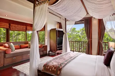 a bedroom with a canopy bed and a couch at Gending Kedis Luxury Villas & Spa Estate in Jimbaran