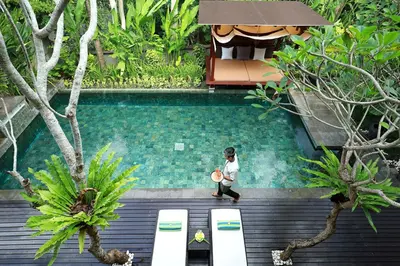 a man standing near a swimming pool with a frisbee at Gending Kedis Luxury Villas & Spa Estate in Jimbaran
