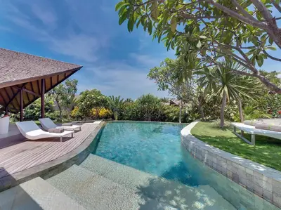 a swimming pool with a deck and chairs next to a house at The Layar - Designer Villas and Spa in Seminyak
