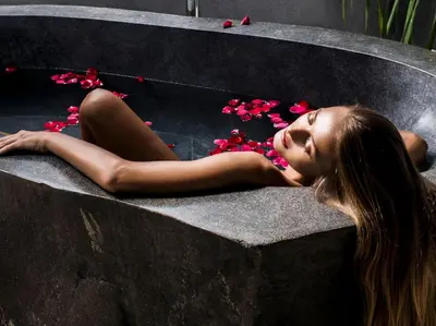 a woman laying on a rock with pink flowers at The Layar - Designer Villas and Spa in Seminyak