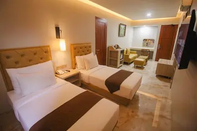 a hotel room with two beds and a living room at Kuta Majesty Hotel in Legian