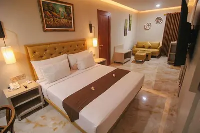 a bedroom with a large bed and a living room at Kuta Majesty Hotel in Legian