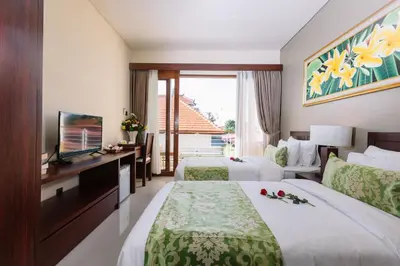 a hotel room with two beds and a television at Kubu Benoa Guest House in Nusa Dua