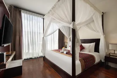 a bedroom with a canopy bed with white curtains at 18 Suite Villa Kuta in Kuta