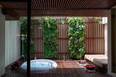 a bathroom with a tub with plants on the wall at Berry Amour Romantic Villas in Seminyak