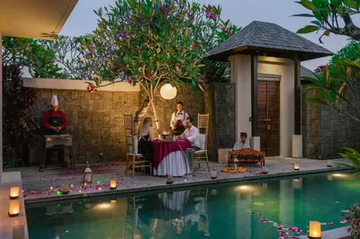 a group of people sitting around a table by a pool at Berry Amour Romantic Villas in Seminyak