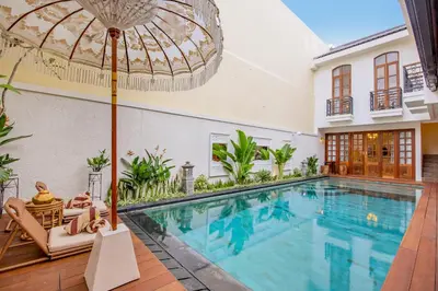 an indoor swimming pool in a house with an umbrella at Villa Casa Adeline in Canggu