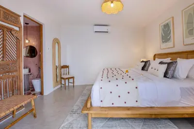 a bedroom with a large white bed and a bench at Villa Casa Adeline in Canggu
